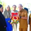 Bupati Banggai Laut Sofyan Kaepa memberikan sembako ke warga di pasar murah yang digelar di kawasan Taman Kota Banggai (Ist)