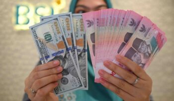 Ilustrasi petugas money changer sedang menunjukkan lembaran rupiah dan dolar AS. (ANTARA FOTO)
