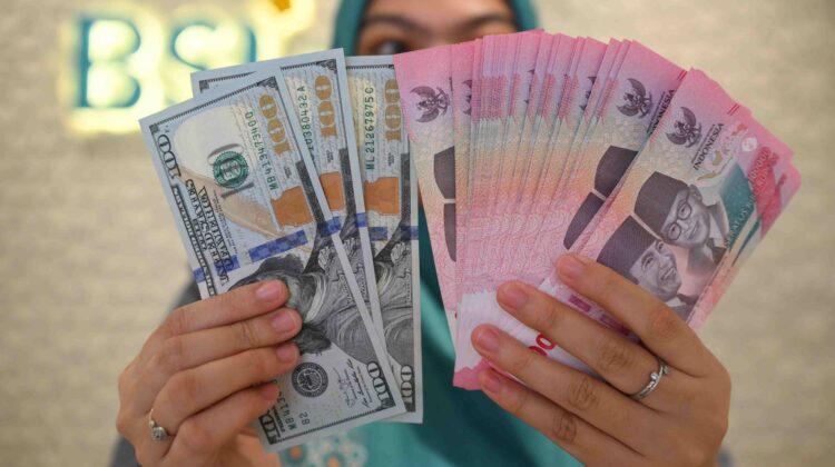 Ilustrasi petugas money changer sedang menunjukkan lembaran rupiah dan dolar AS. (ANTARA FOTO)